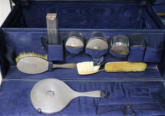 A George V travelling toilet set, with eight assorted silver mounted items and two lids, in a blue leather case.